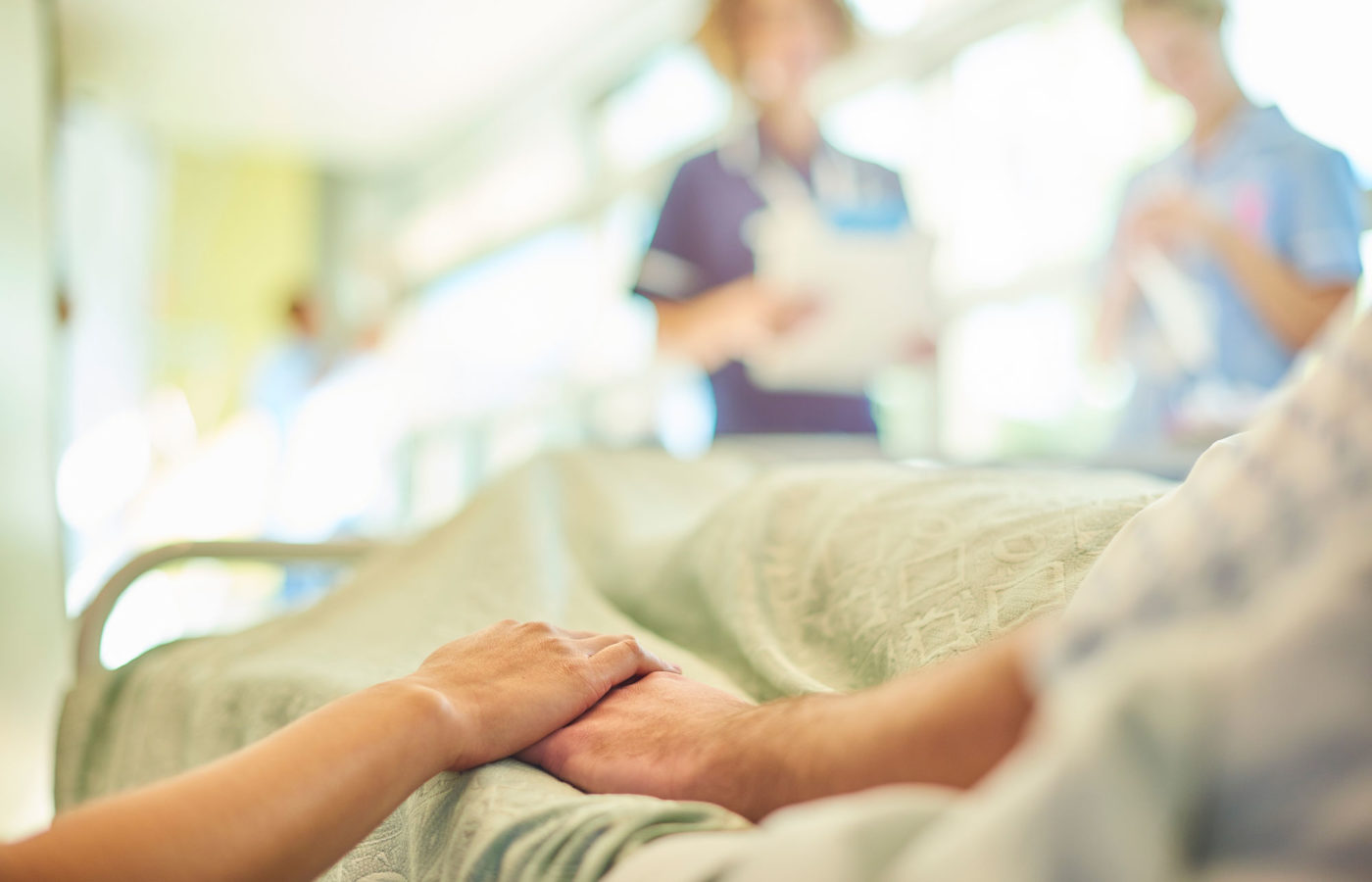 holding a patient's hand in a hospital bed