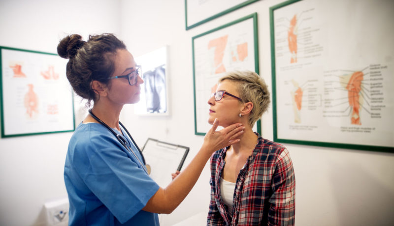 Female doctor checks young female's throat in exam