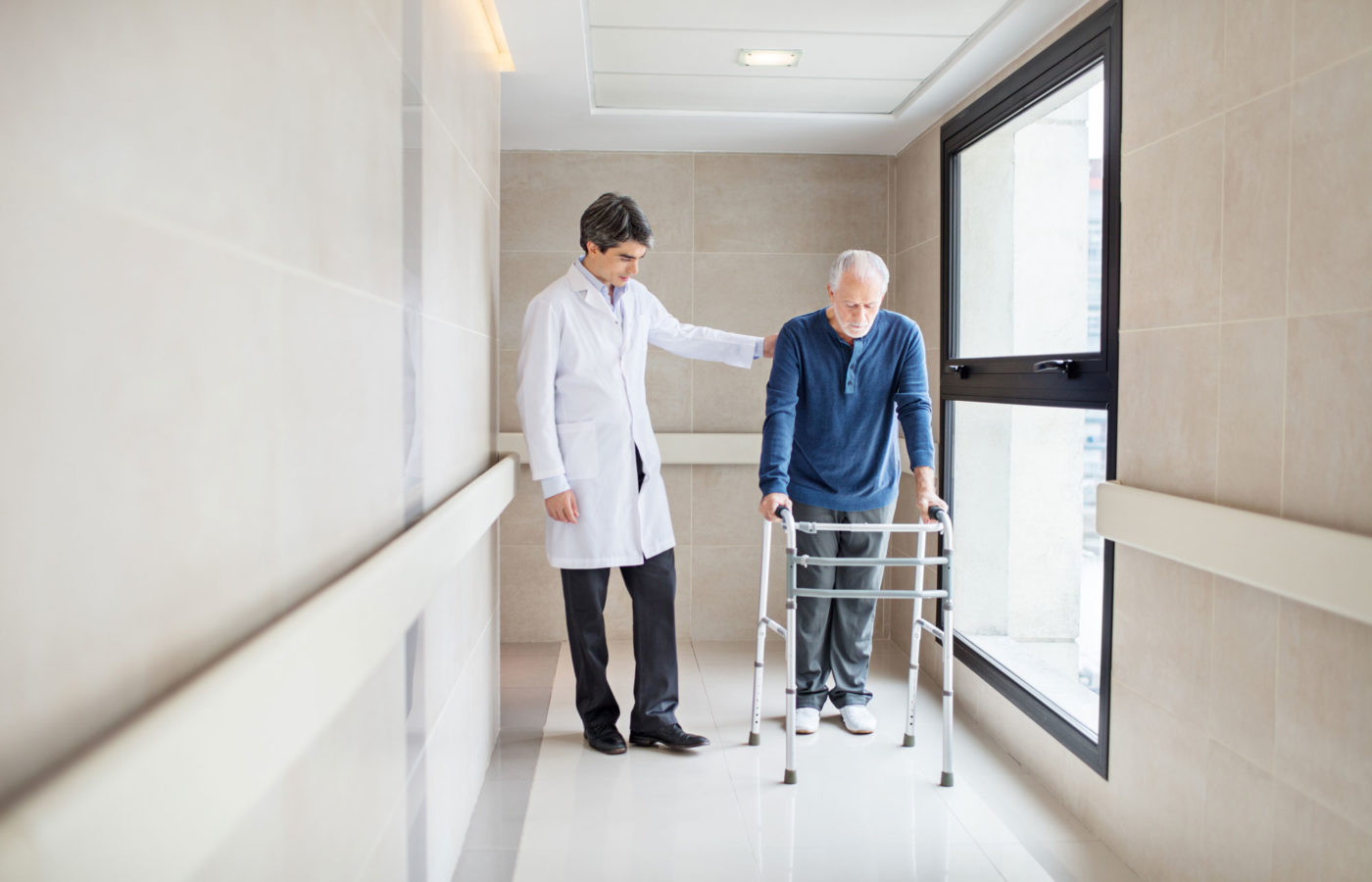Elderly man with a walker is helped by a physician