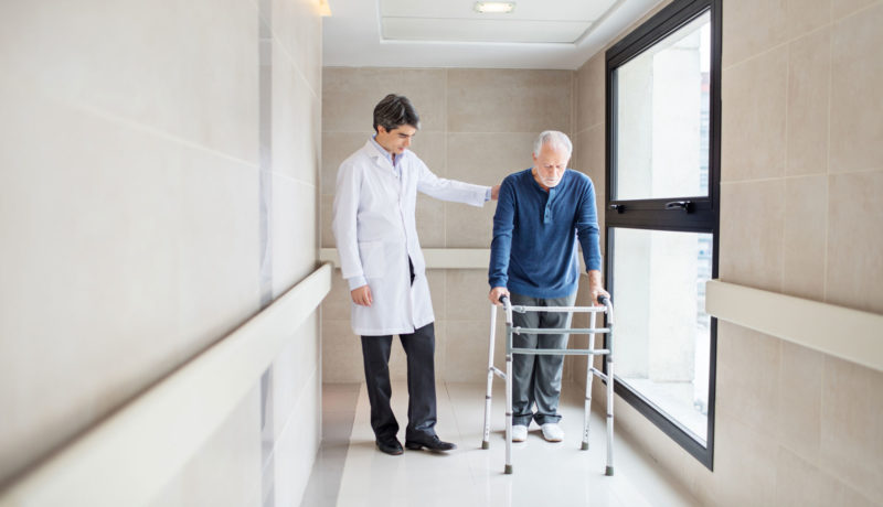 Elderly man with a walker is helped by a physician