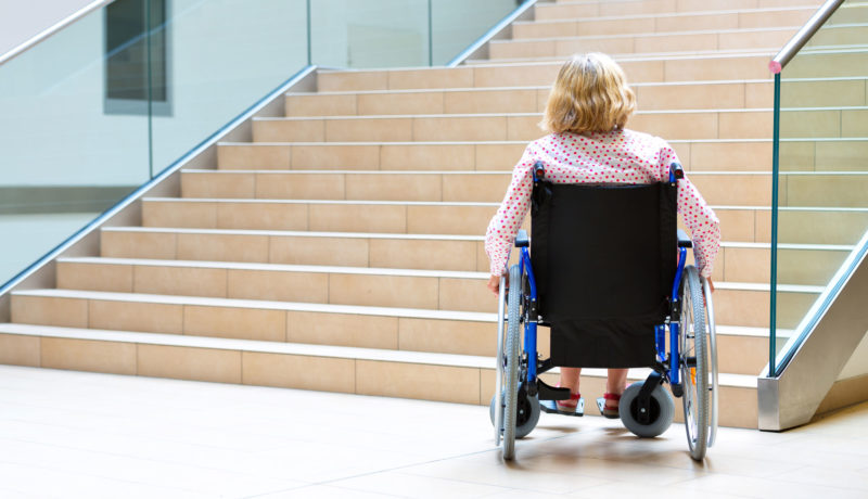 Woman in a wheelchair faces a stairway