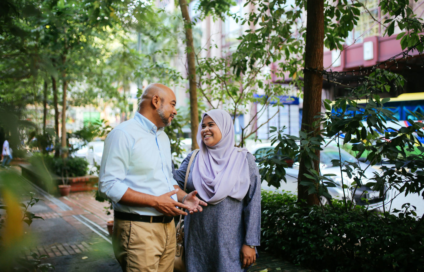 Muslim couple walk through a park in the sunshine