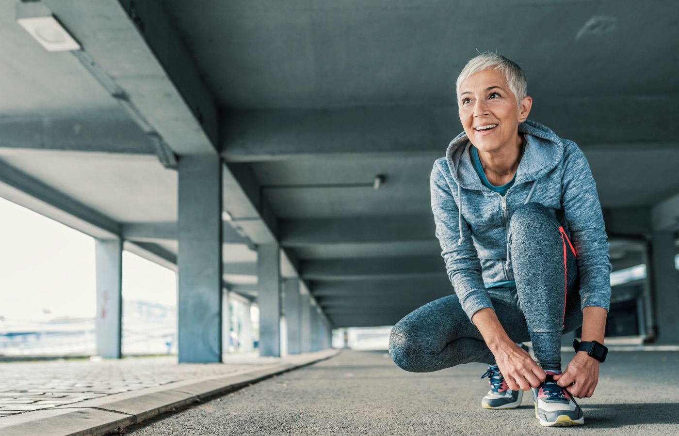 Mature woman ties her shoe as she sets out for a run