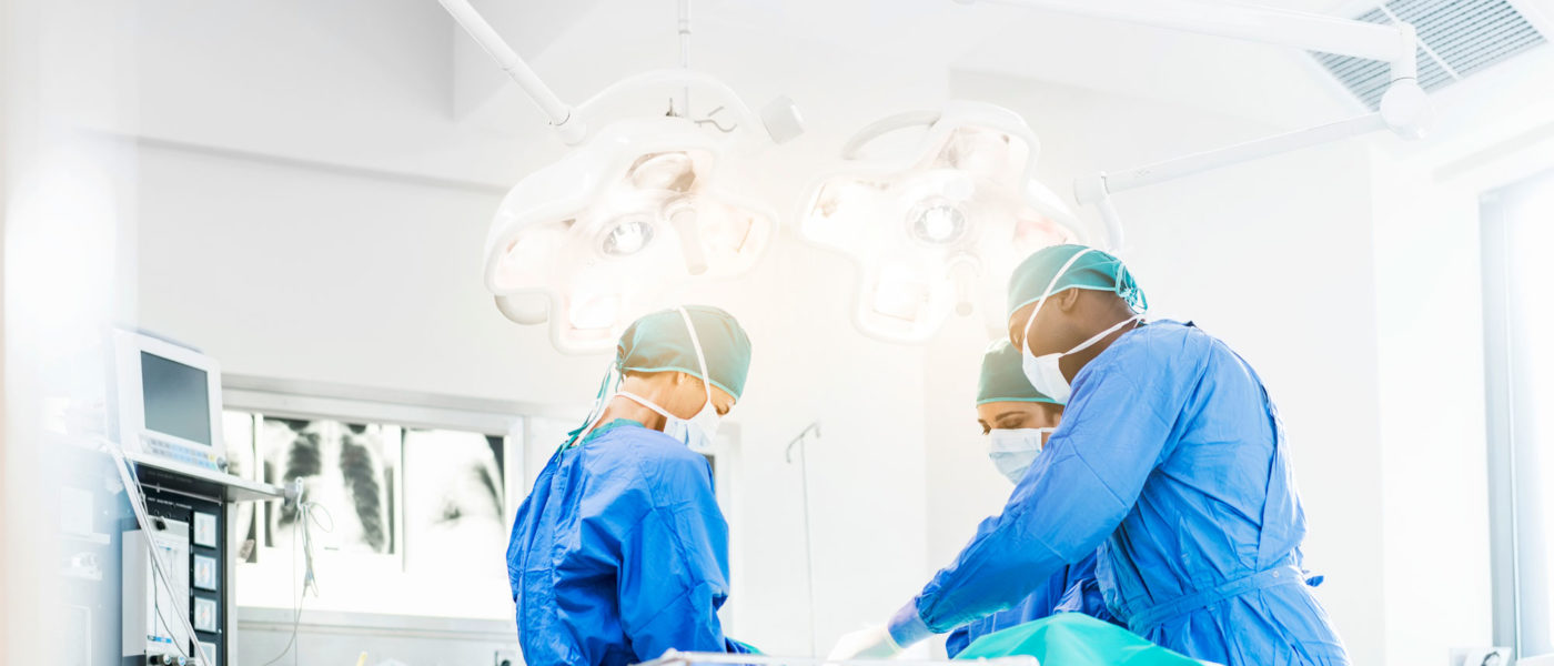Surgeons work on a patient in a brightly lit operating room