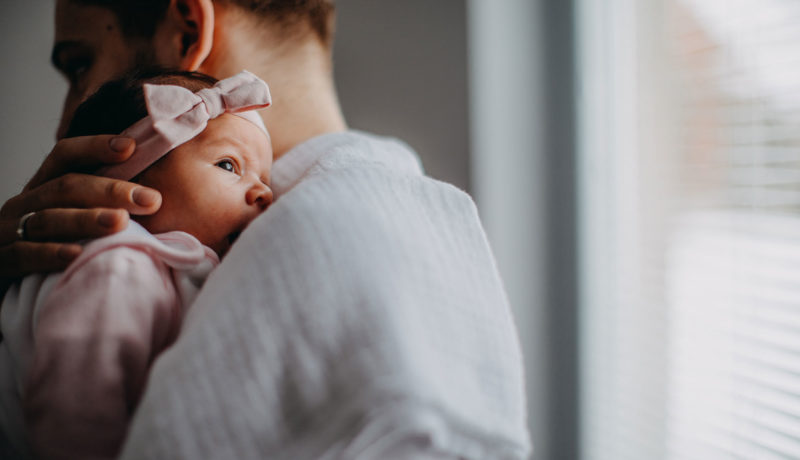 Newborn baby is held by father