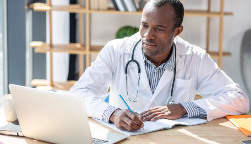 Male doctor takes notes on a laptop