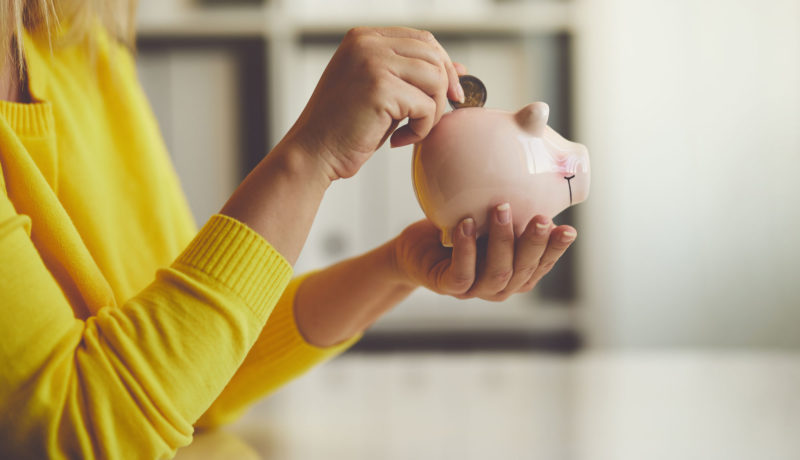 woman drops quarter in piggy bank for investments